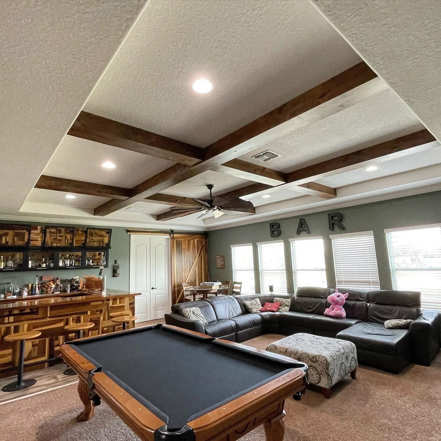 Man cave with beam ceiling, bar, and pool table